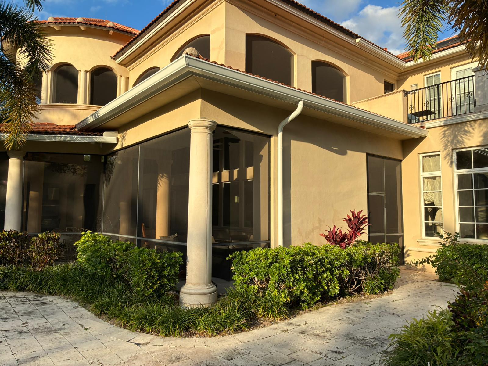 White seamless gutter system and downspout detail on a home with a Mediterranean-style tile roof